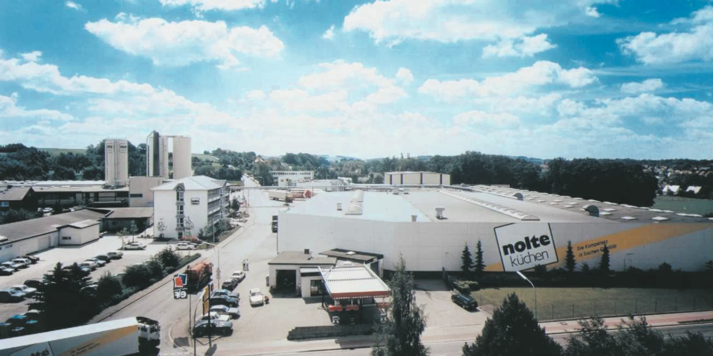 Eine große Fabrikanlage mit dem Schriftzug "nolte küchen" auf dem Dach unter einem bewölkten Himmel.