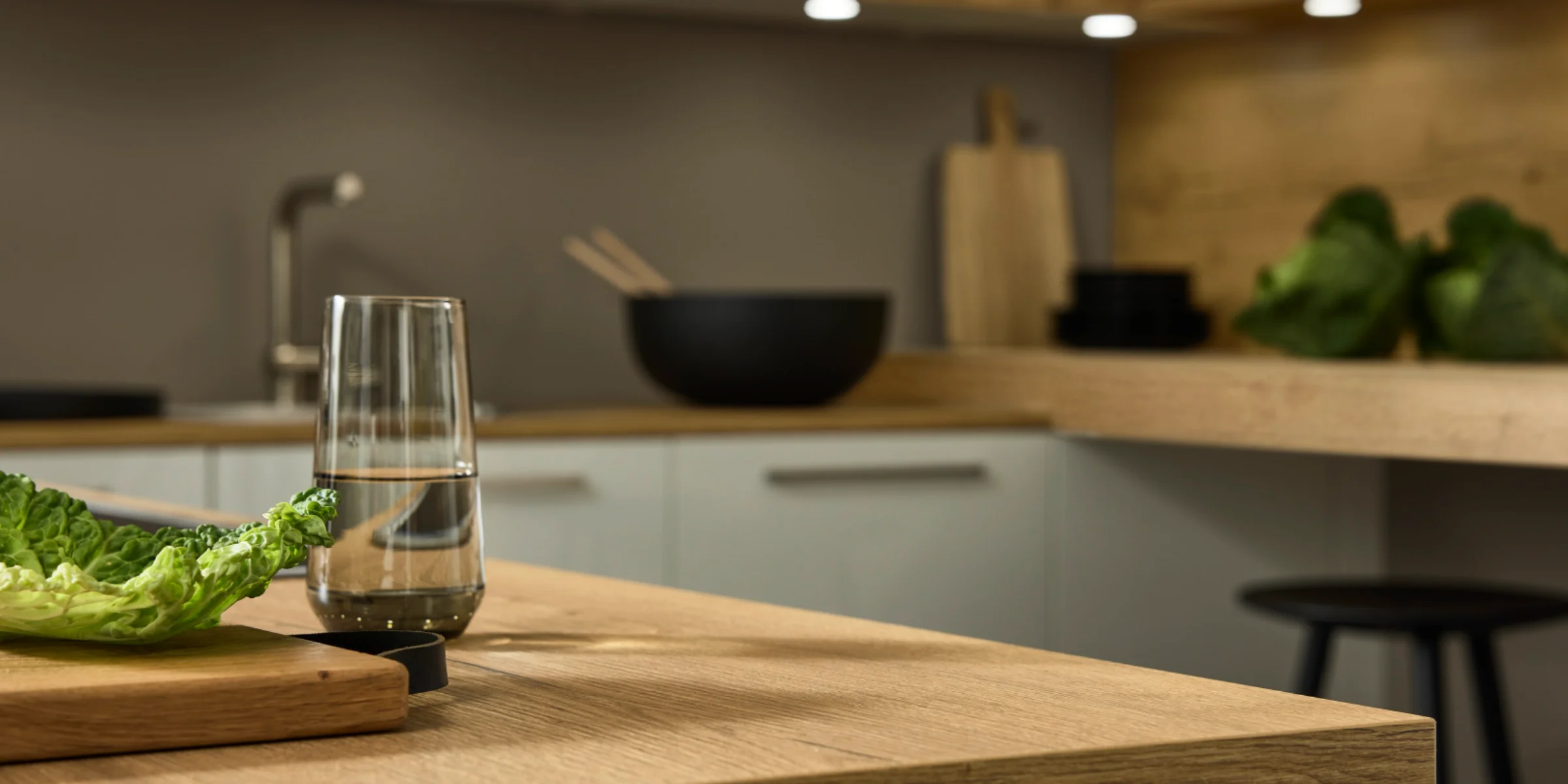 Eine moderne Küche mit Holzoberflächen und Salat auf dem Tisch, gestaltet von Nolte Küchen.