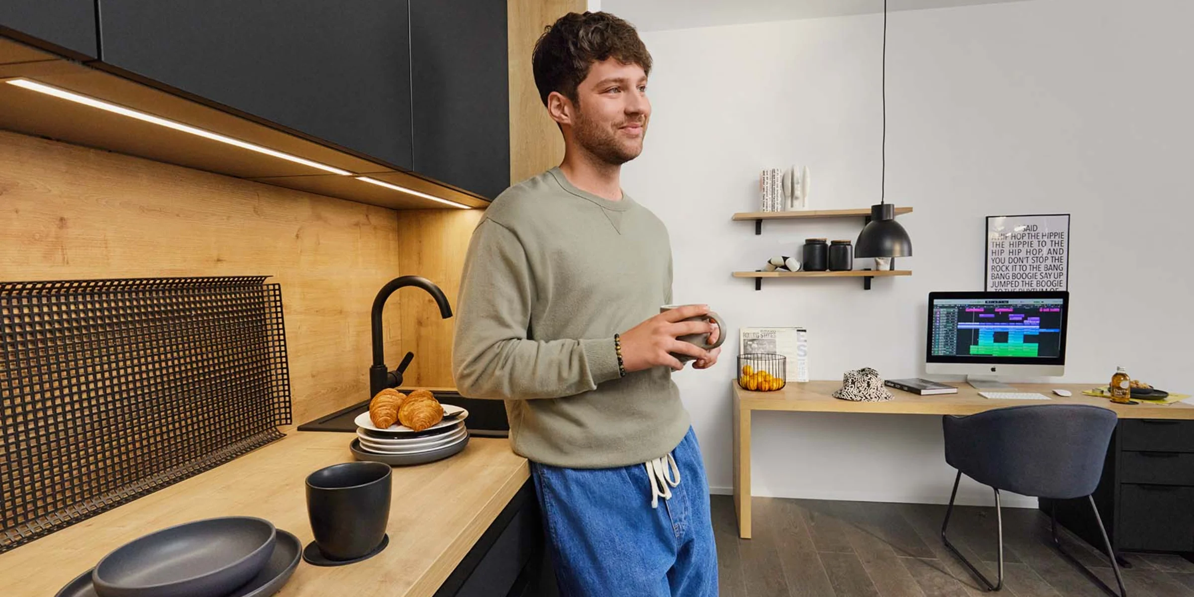 Un uomo in una cucina moderna con dettagli in legno e arredi neri, Nolte Kitchen.