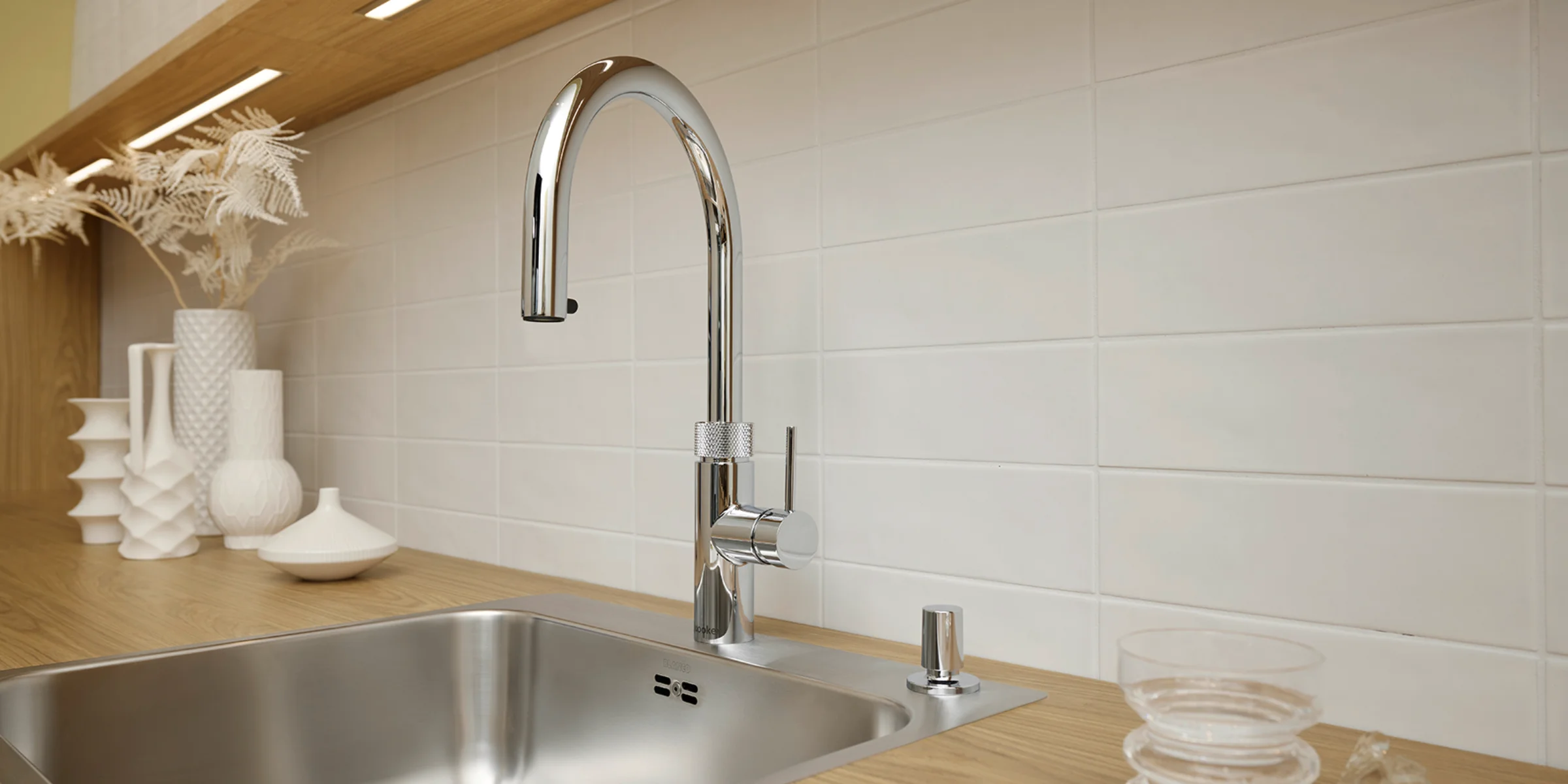 Eine moderne Küchenspüle mit Holzarbeitsplatte und dekorativen Vasen, Nolte Küchen.