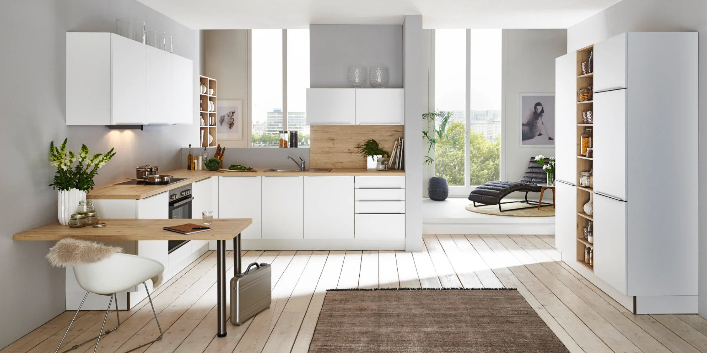 Helle Nolte Küche mit dem Frontenprogramm PLUS in Weiß softmatt, kombiniert mit Holzarbeitsplatten und integriertem Arbeitsplatz in offener, lichtdurchfluteter Wohnumgebung.