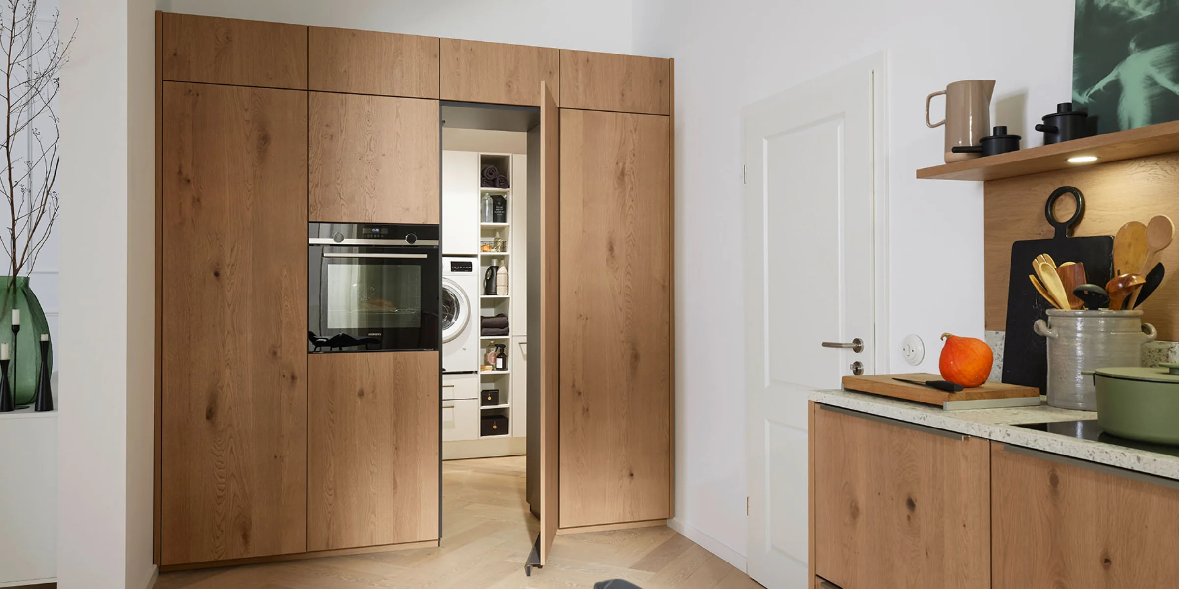 Ein Hauswirtschaftsraum mit Holzschränken und integrierten Geräten, Teil der Nolte Hauswirtschaftsräume.