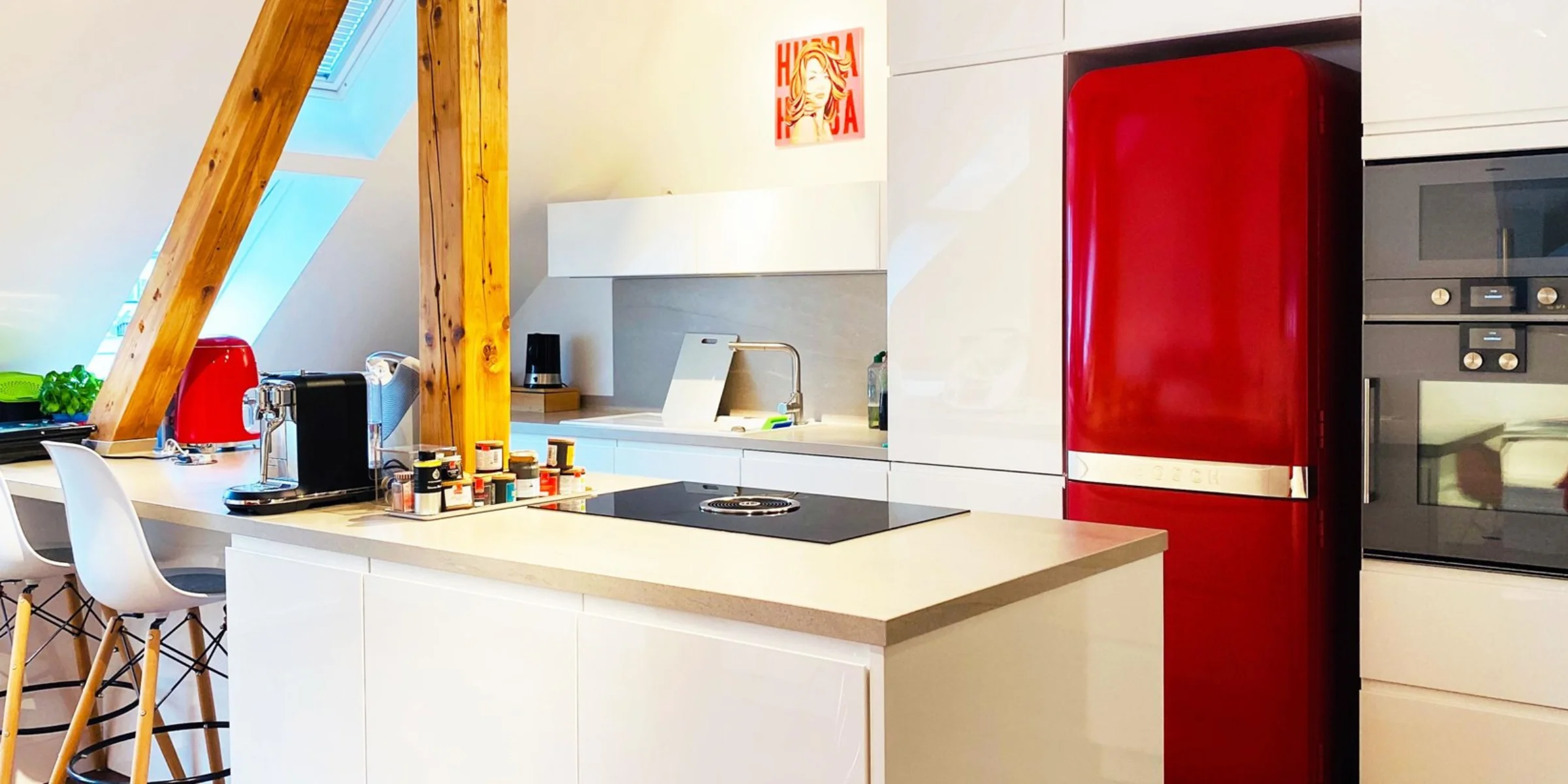 Eine moderne Küche mit rotem Kühlschrank und Kochinsel, Nolte Küchen.