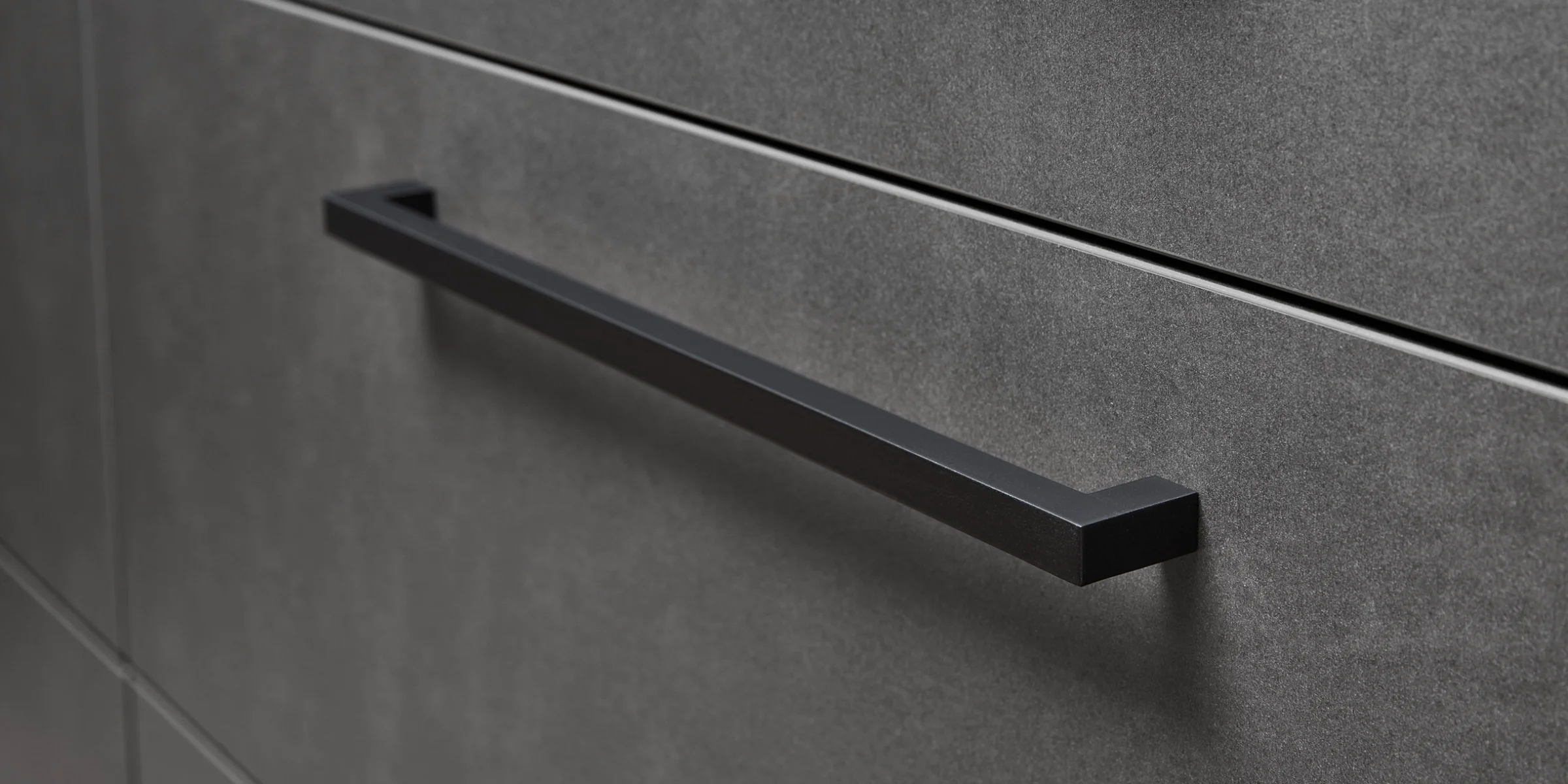 Graue Küchenschränke mit schwarzen Griffen, elegant gestaltet von Nolte Küchen.