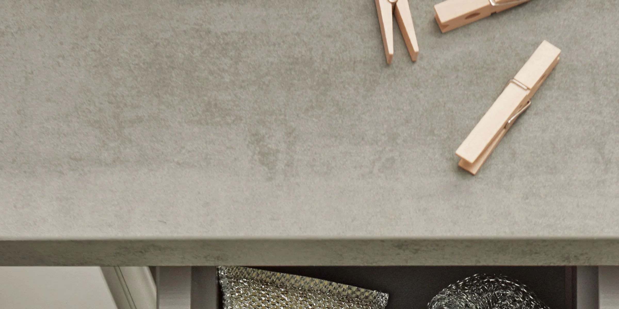 Eine Schublade mit Metallreinigungsutensilien und Holzklammern auf einer Betonoberfläche, Nolte Hauswirtschaftsräume.