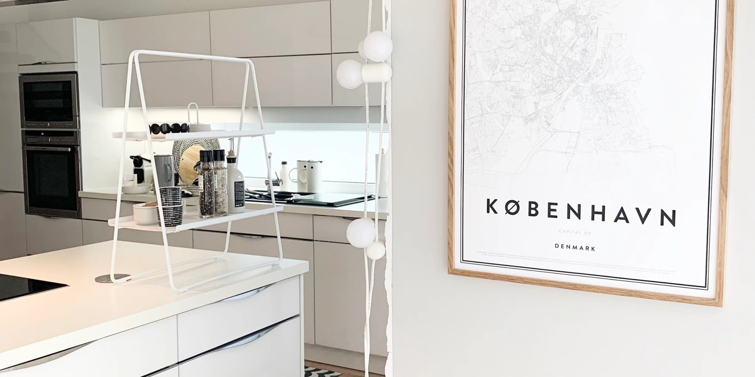 In der modernen Küche mit weißen Schränken ist ein "København"-Poster an der Wand zu sehen. Nolte Küchen.