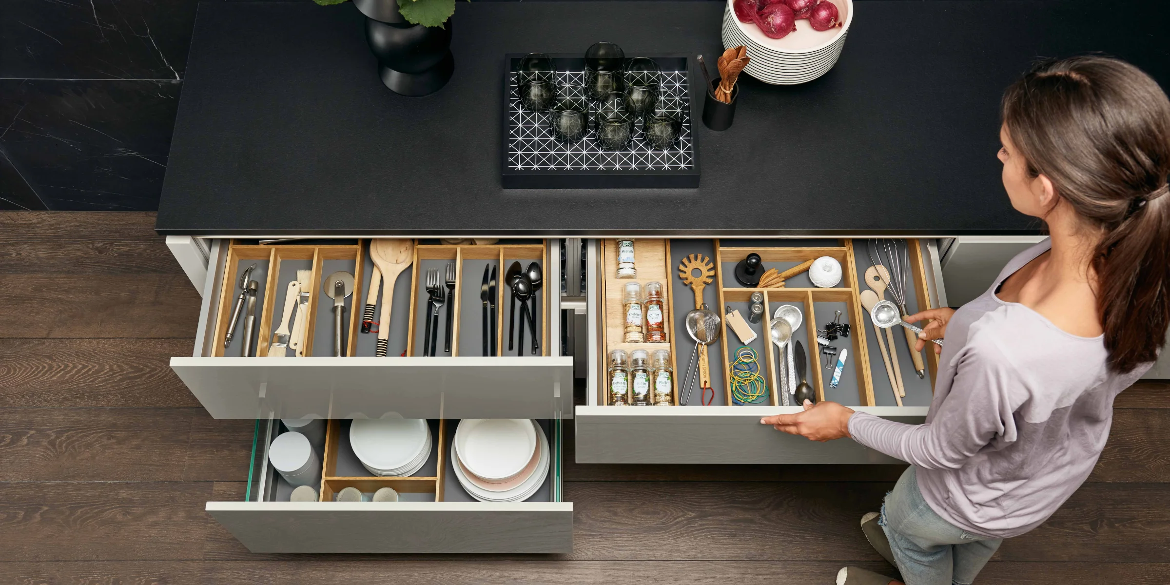 Eine Frau sortiert Küchenutensilien in einer modernen Nolte Küchen Schublade.