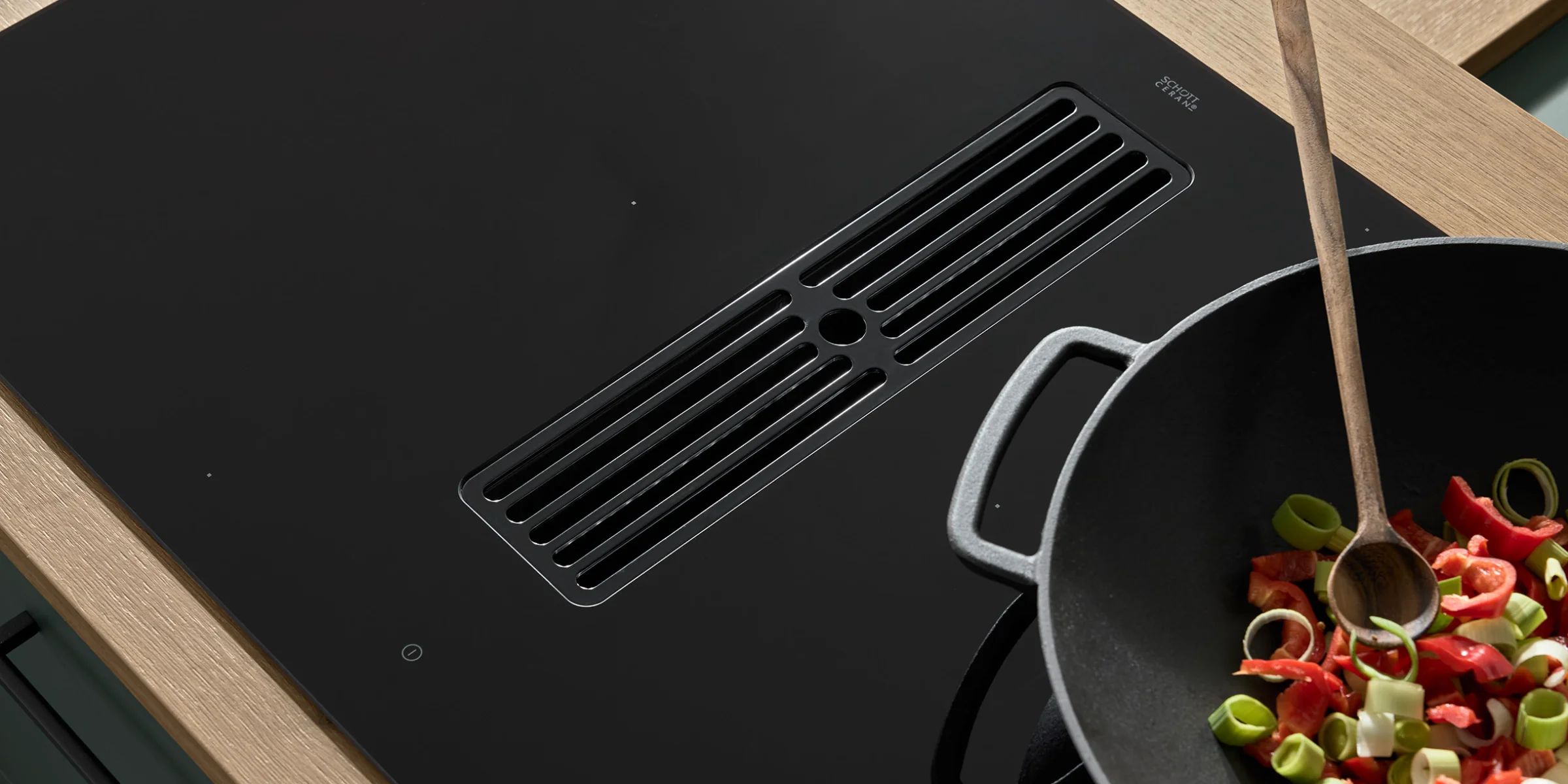 Ein moderner Kochfeldabzug mit Wok und Gemüse in einer Nolte Küchen Umgebung.