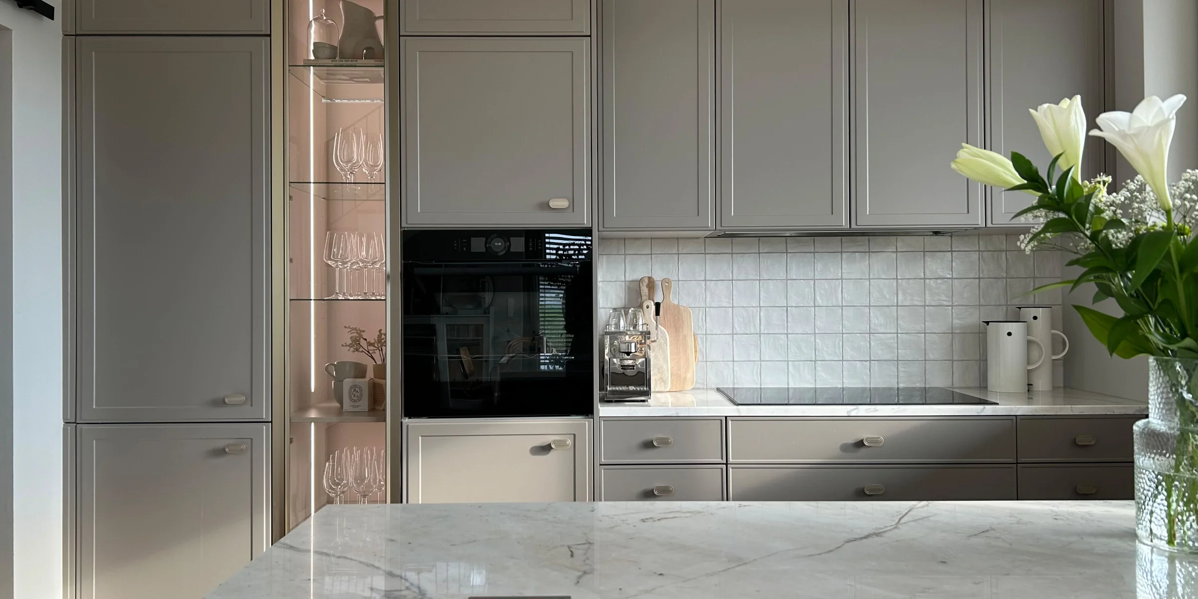A modern kitchen with gray cabinets and a marble island from the Nolte Kitchen collection.