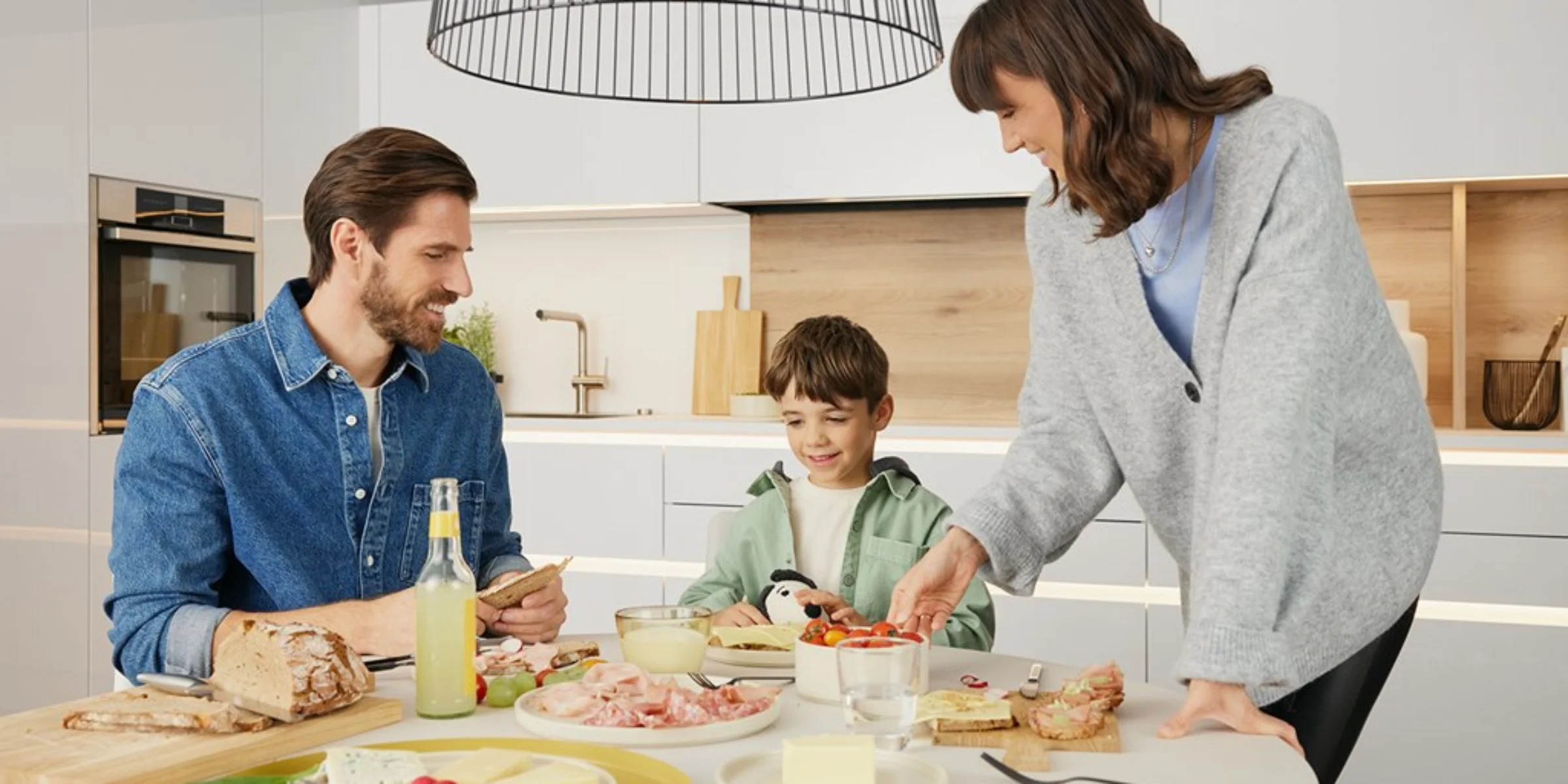 Eine Familie bereitet Frühstück in einer modernen Küche vor, Nolte Küchen.