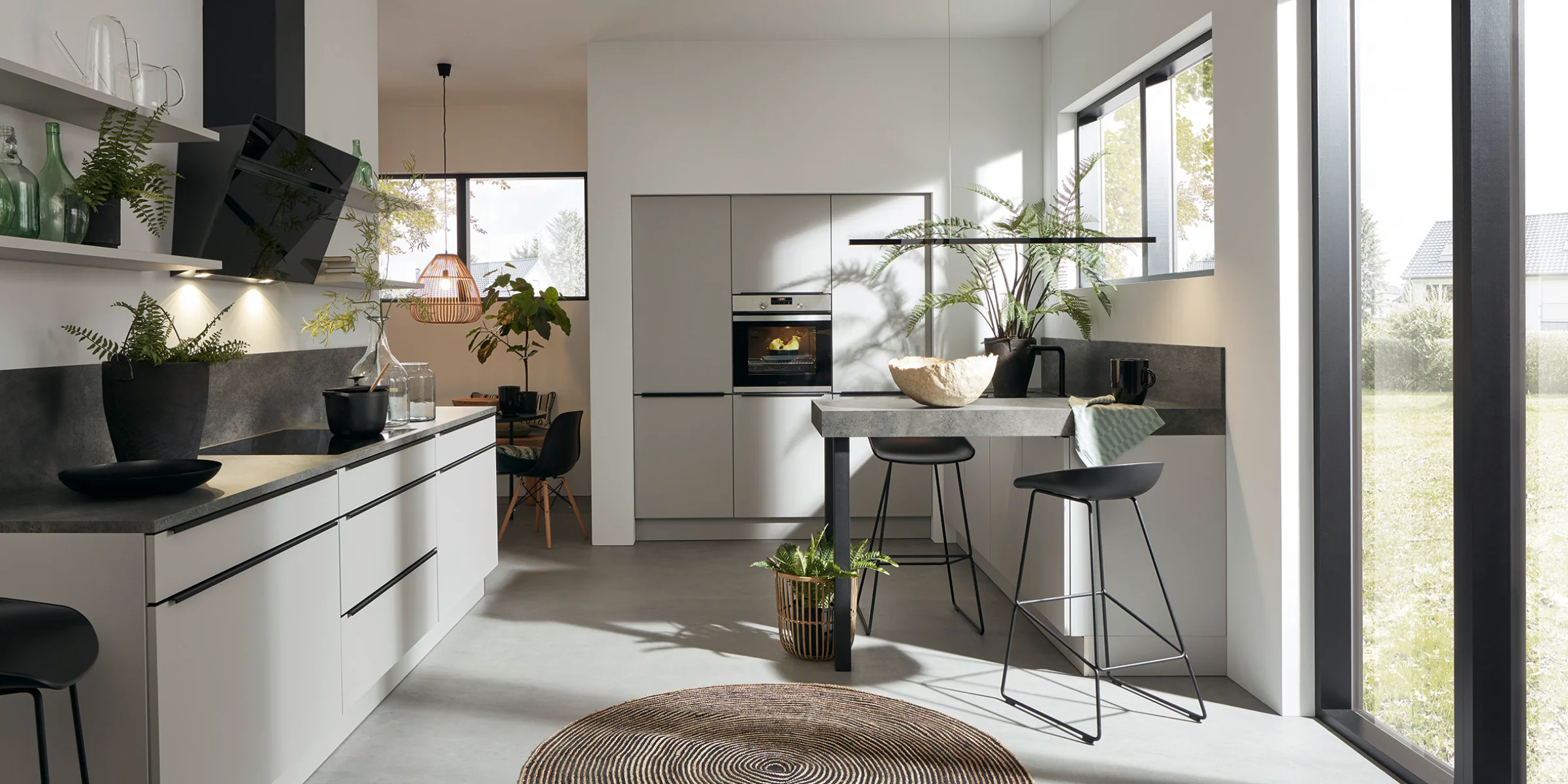 Eine moderne Küche mit Kochinsel und großen Fenstern, gestaltet von Nolte Küchen.