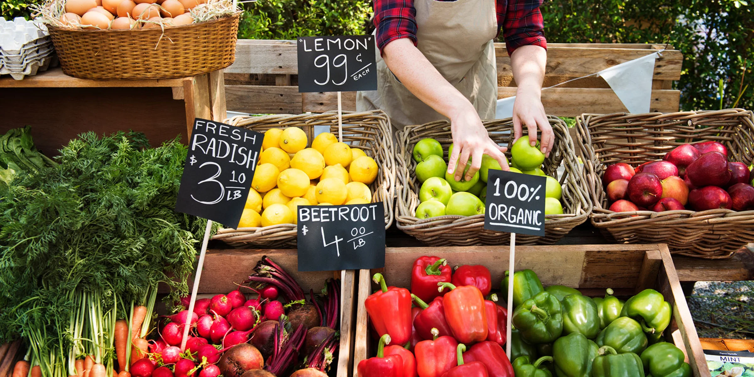 Ein Marktstand mit frischem Gemüse und Obst, darunter Paprika, Radieschen und Äpfel.