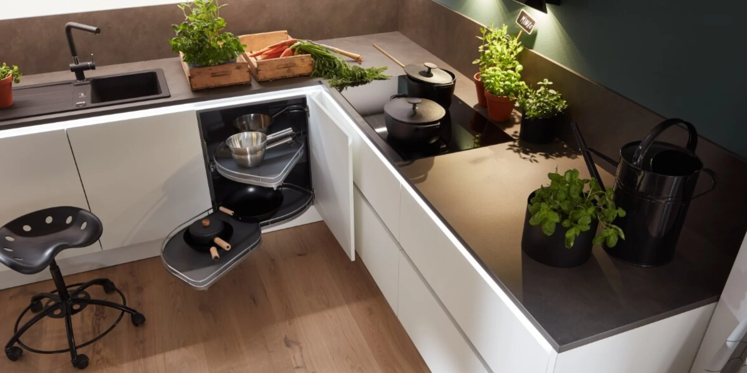 Ergonomisch gestaltete Nolte Küche mit dem Frontenprogramm PLUS in Weiß Softmatt, optimaler Arbeitshöhe und durchdachter Stauraumorganisation – frische Kräuter und geöffnete Schubladen zeigen smarte Küchendetails.
