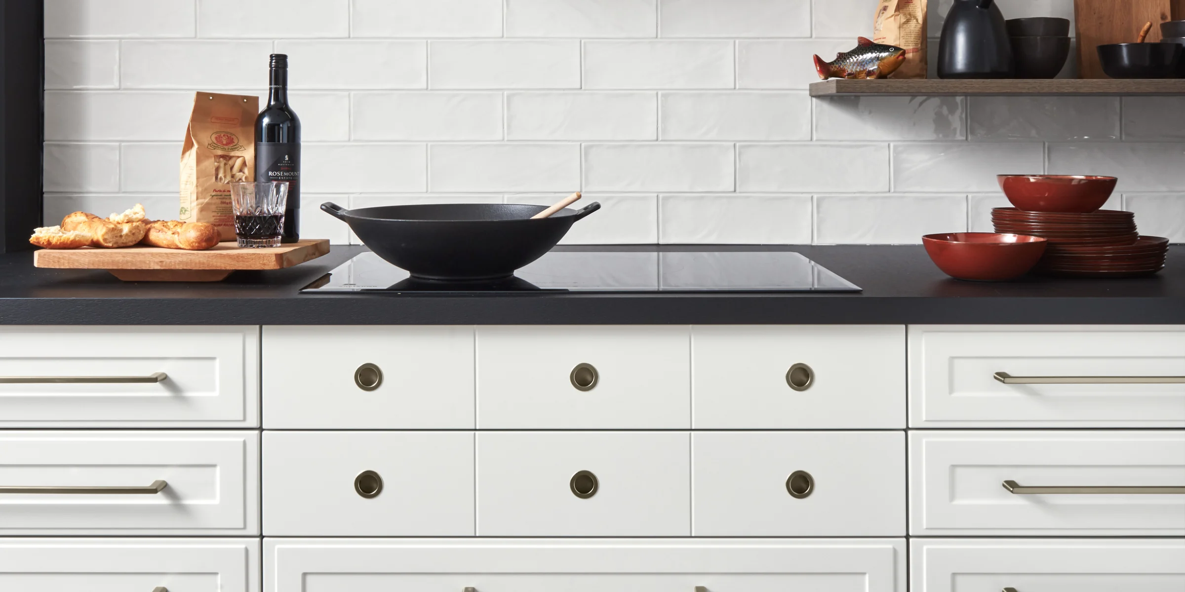 Eine moderne Küche mit weißer Schrankfront und dunkler Dunstabzugshaube. Nolte Küchen.