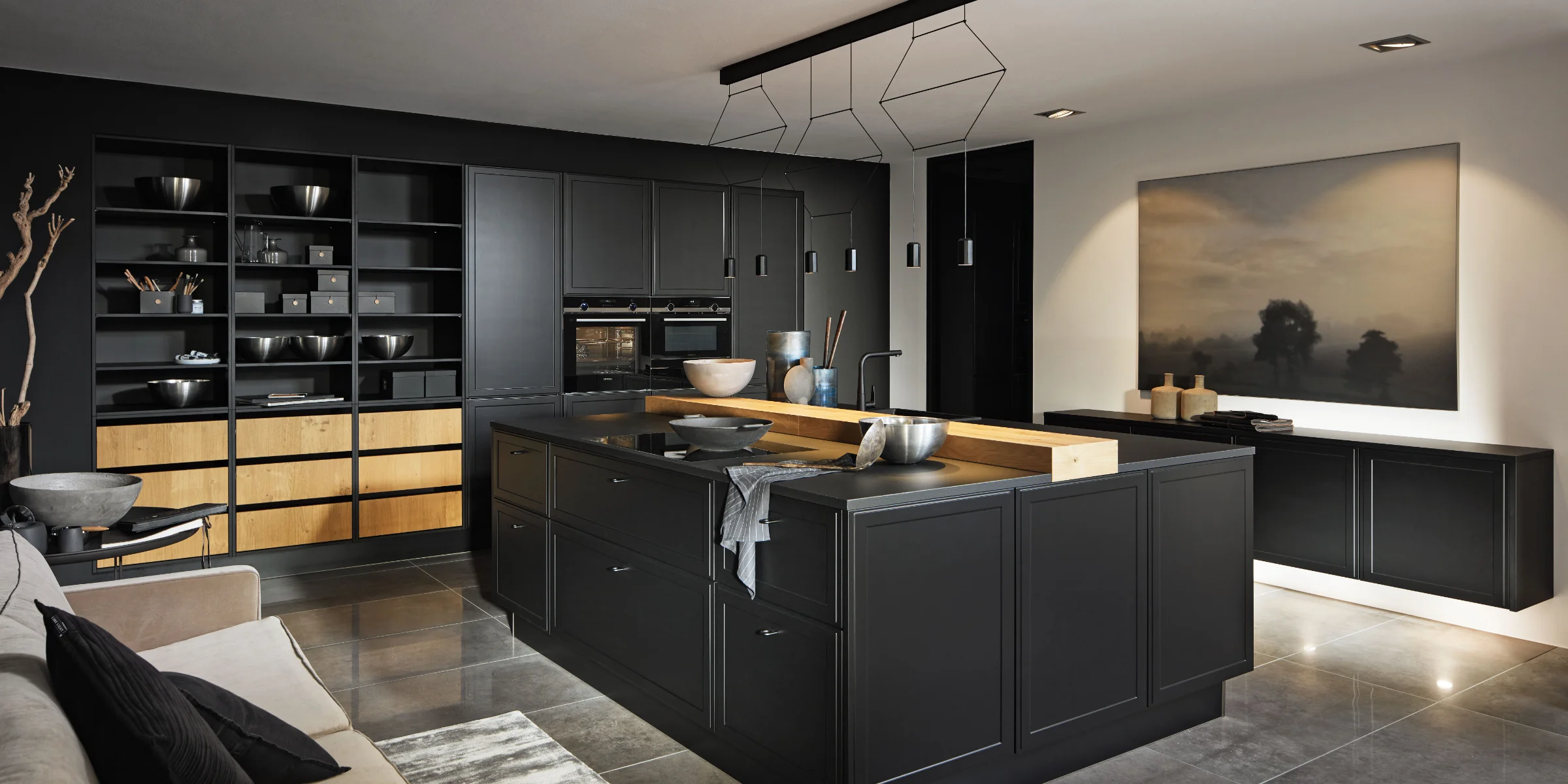 Una cocina moderna en tonos oscuros con isla y elegantes armarios de Nolte Cocina.