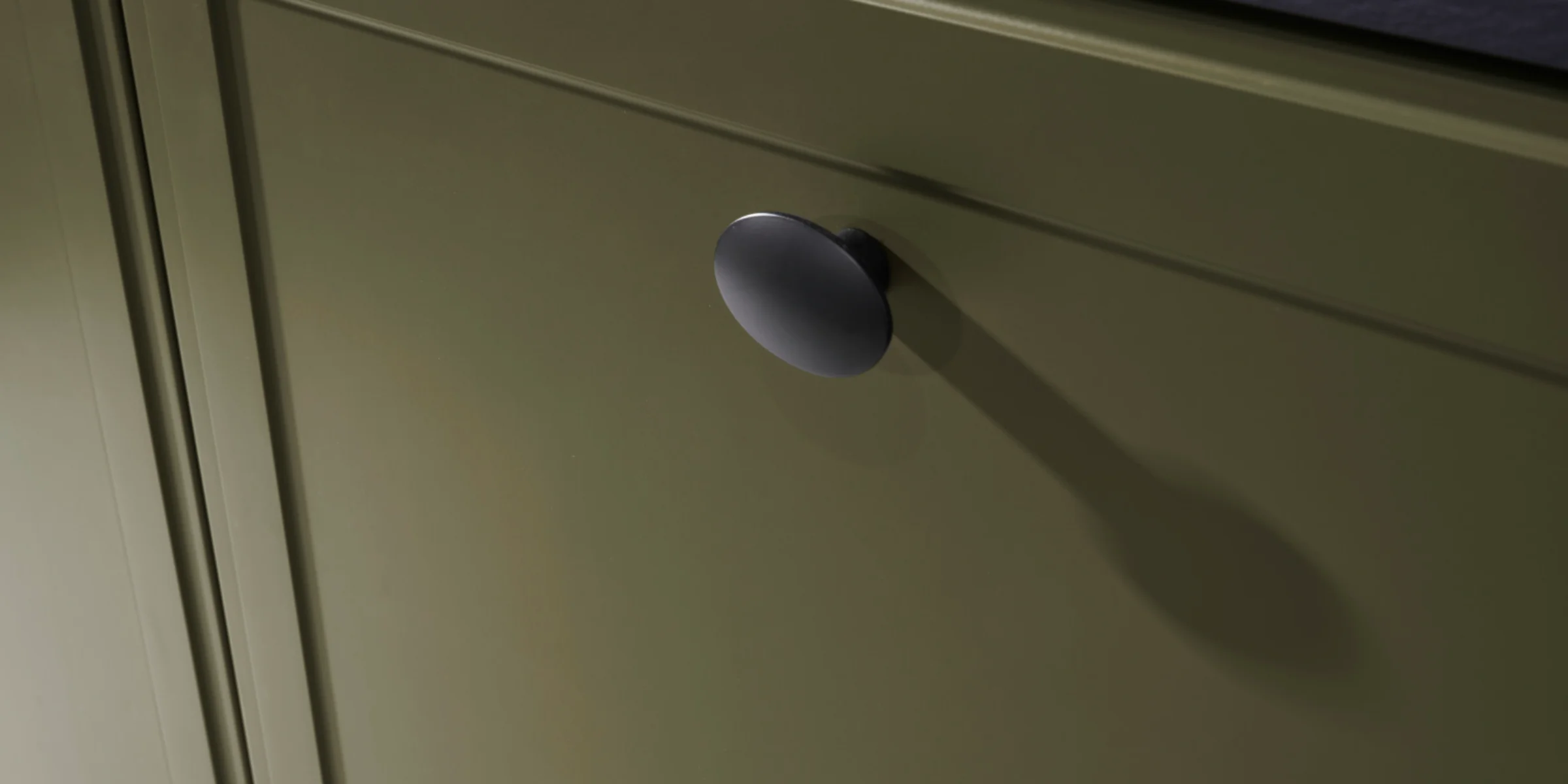 Ein grüner Küchenschrank mit schwarzem Knopf, Teil von Nolte Küchen.