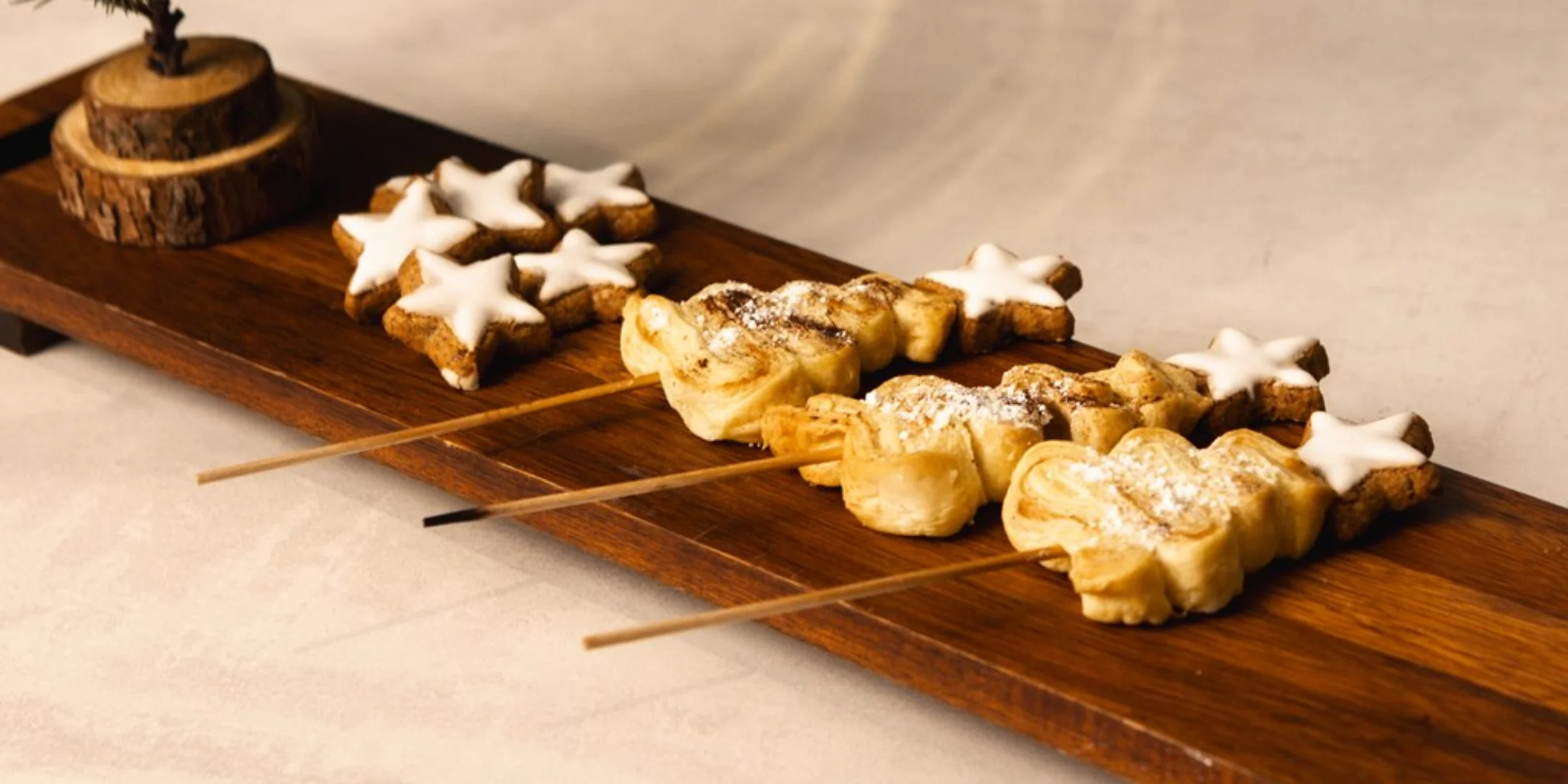 Auf einem Holztablett liegen sternförmige Kekse und Gebäck am Spieß.
