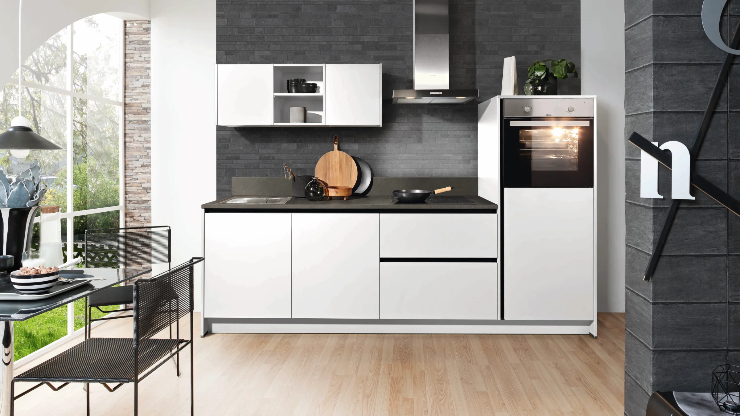 Moderne weiße Küche mit dunkler Rückwand und integriertem Backofen. Express Küchen.