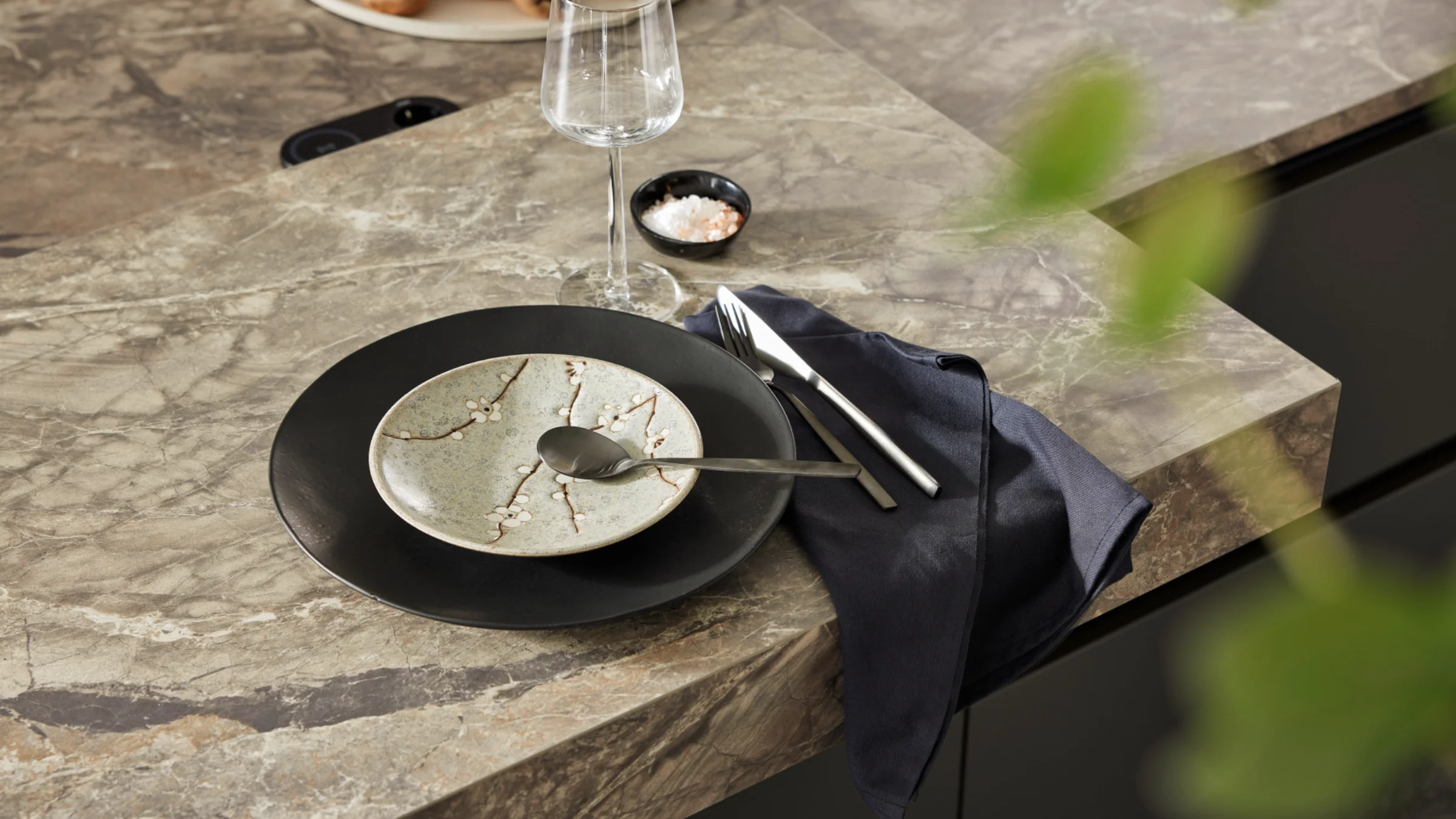 Ein stilvoll gedeckter Tisch mit modernem Geschirr auf einer Küchenarbeitsplatte von Nolte Küchen.