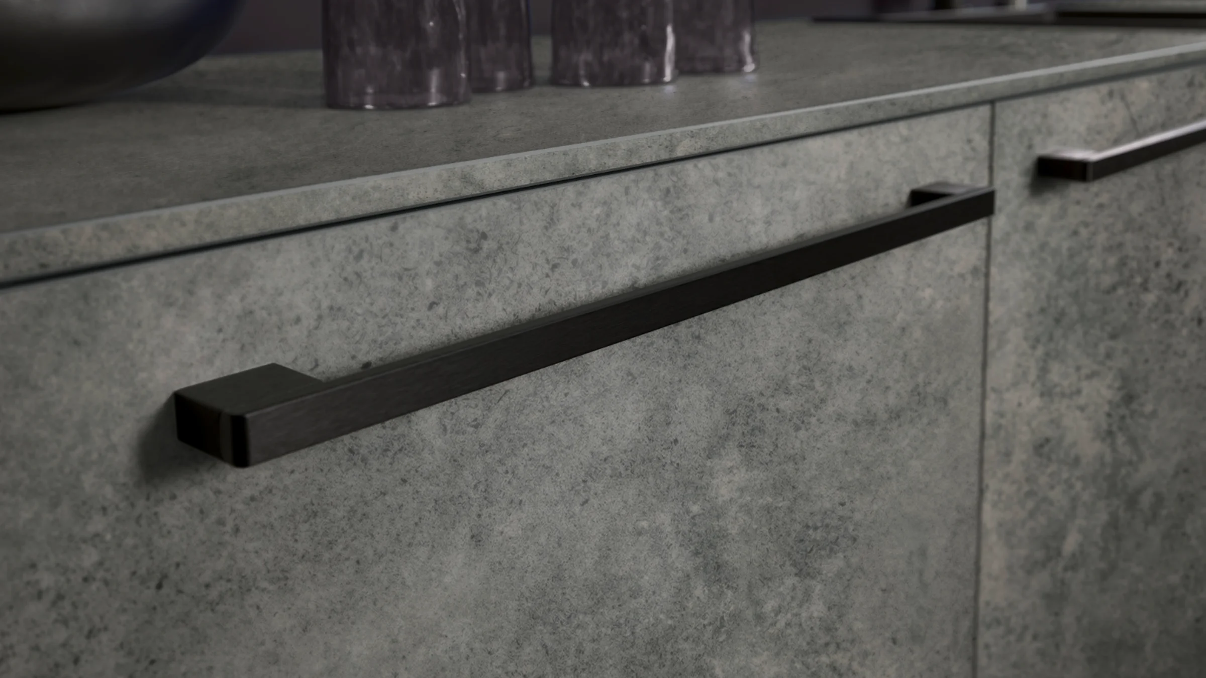 Eine moderne Küchenschrankfront mit grauer Steinoptik und schwarzen Griffen, Nolte Küchen.