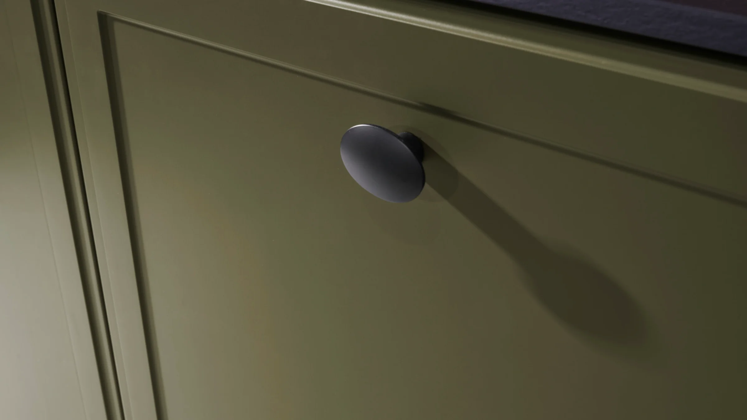 Ein grüner Küchenschrank mit schwarzem Knopf, Teil von Nolte Küchen.