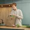 Ein Mann steht in einer modernen Küche von Nolte Küchen und räumt Einkäufe aus einer Jutetasche auf die Arbeitsplatte.