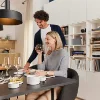 Ein Paar genießt eine Mahlzeit in einem modernen Raum mit Bücherregal und Küche, Nolte Living.