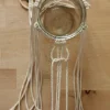Ein Glas wird mit Makramee-Schnüren auf einem Holztisch dekoriert.