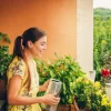 A woman in a yellow dress waters plants on a balcony with a green landscape in the background.