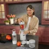 Eine Frau bereitet in einer modernen Küche mit roten Schränken einen Smoothie zu. Nolte Küchen.