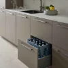 Eine moderne Küche mit geöffnetem Schrank und Wasserkisten, ausgestattet von Nolte Küchen.