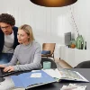 Ein Paar arbeitet gemeinsam an einem Laptop in einem modernen Wohnzimmer mit Nolte Living.