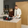 Ein Paar betrachtet ein Kochbuch in einer modernen Küche mit Holzdetails, Nolte Küchen.