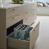 Eine moderne Küche mit geöffneter Schublade voller Flaschen. Nolte Küchen.