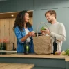 A couple unpacks vegetables in a modern Nolte kitchen setting.