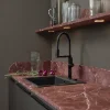 Eine stilvolle Küche mit roten Marmorarbeitsflächen und modernen Regalen. Nolte Küchen.