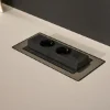 Eine schwarze Steckdose ist in eine helle Arbeitsfläche integriert. Nolte Küchen.