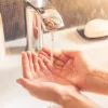 Eine Person hält ihre Hände unter fließendes Wasser im Badezimmer, Nolte SPA.
