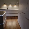 A modern kitchen with wooden floors and illuminated cabinets by Nolte Kitchen.
