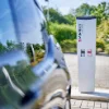 Ein Elektroauto steht vor einer Ladestation im Freien, umgeben von Bäumen. Nolte Küchen.