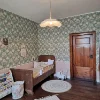 Un dormitorio infantil con cama de madera, papel tapiz de flores y alfombra redonda sobre suelo de madera.