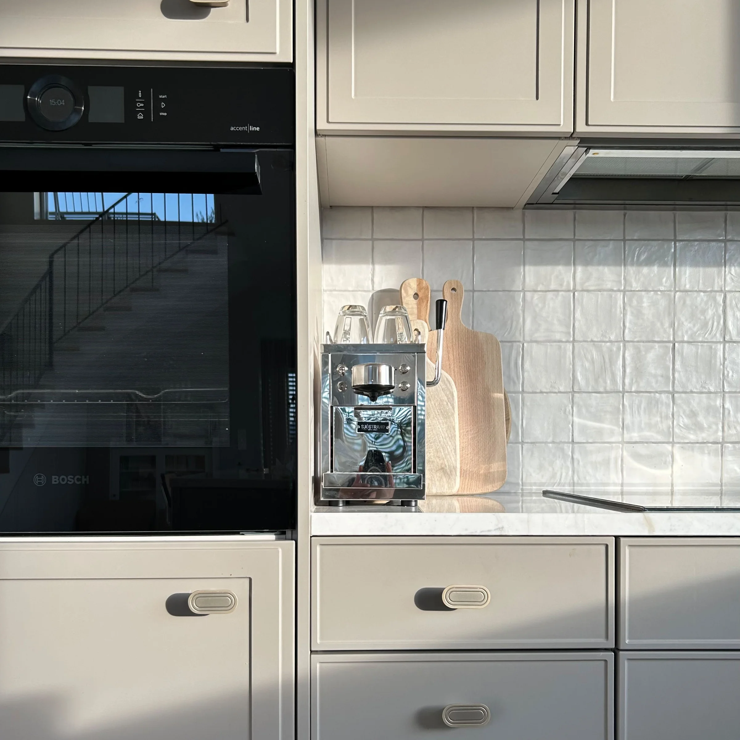 Cucina moderna con armadi bianchi e dettagli in legno, completata perfettamente da Nolte Kitchen.