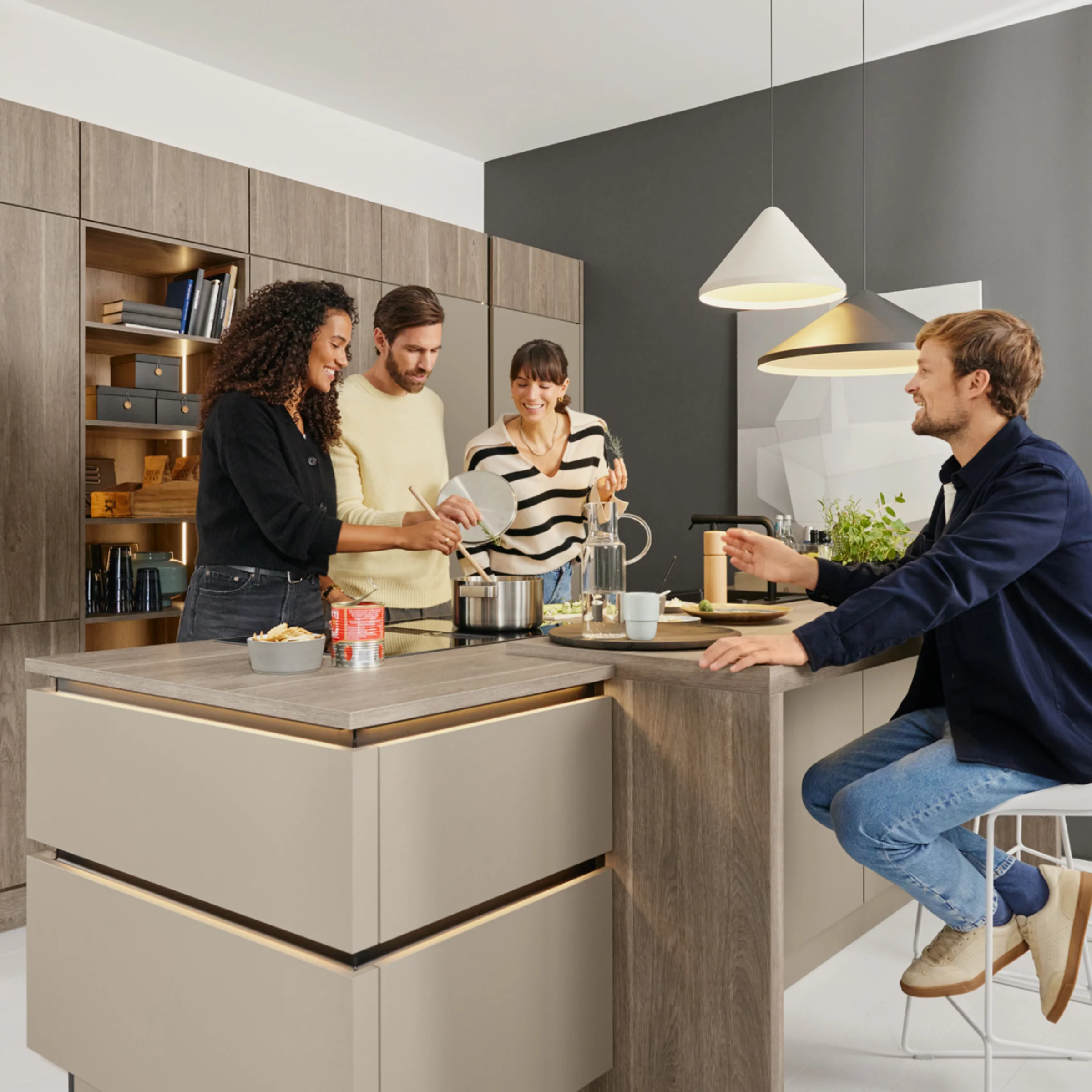 Eine moderne Küche mit vier Personen beim gemeinsamen Kochen. Nolte Küchen.