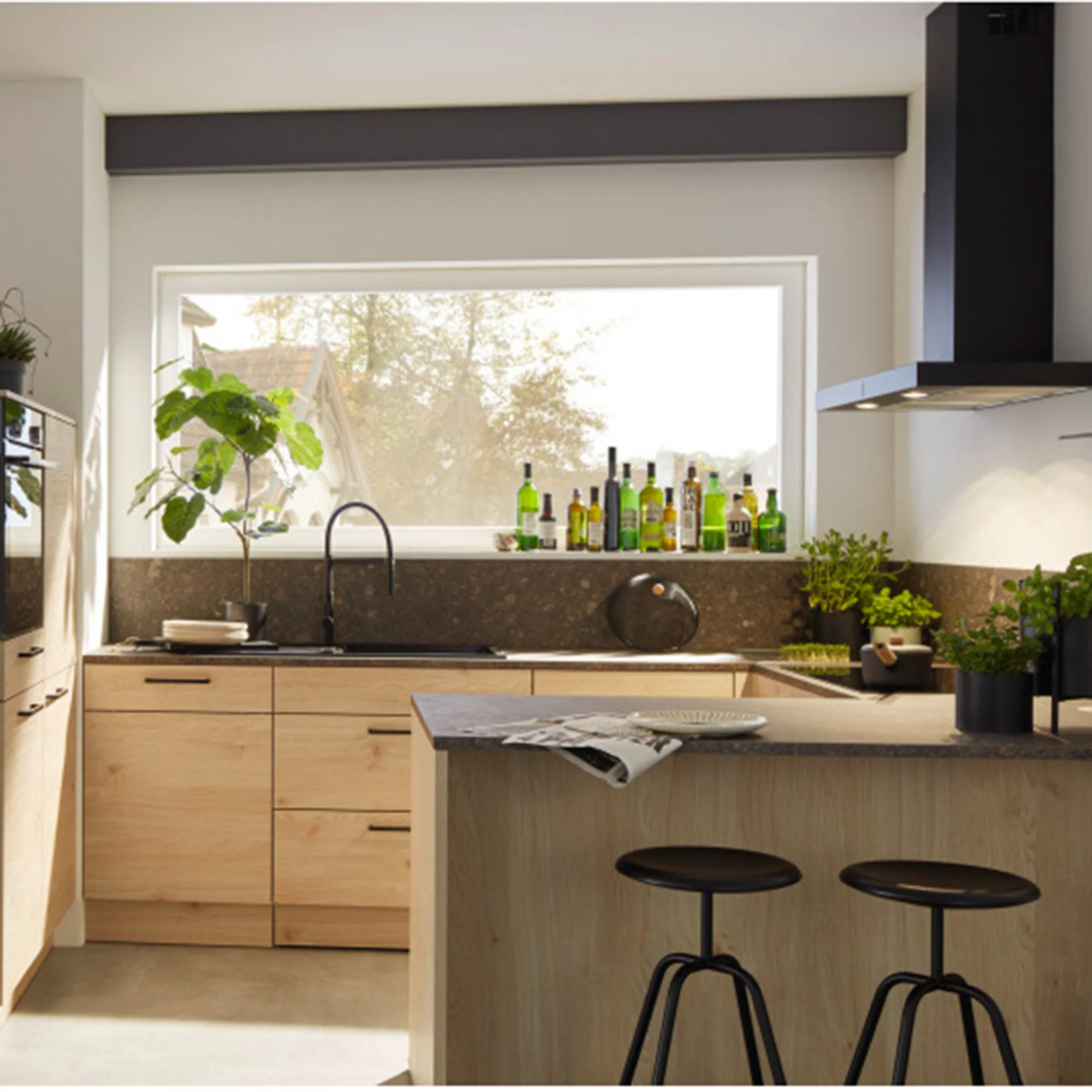 Eine moderne Küche mit Holzschränken und Pflanzen, beleuchtet durch ein großes Fenster. Nolte Küchen.