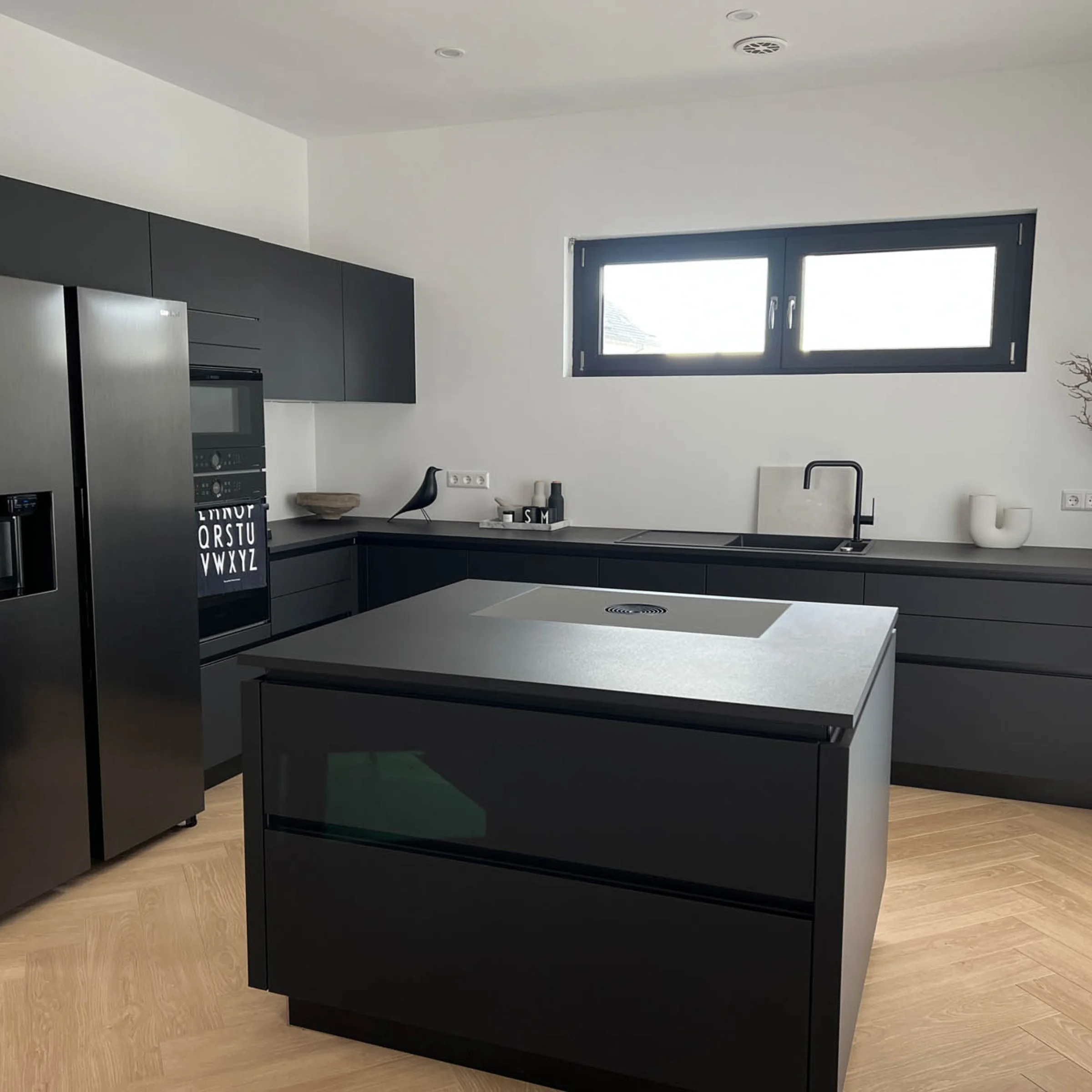Moderne Küche mit schwarzer Insel und Geräten, die von Nolte Küchen gestaltet wurde.