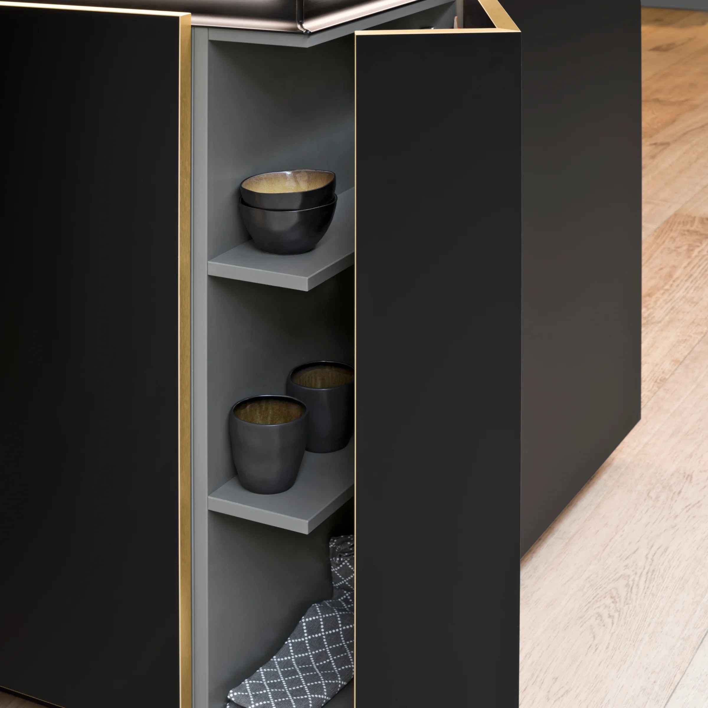 Cuisine moderne noire avec porte de placard ouverte et vaisselle, par Nolte Kitchen.