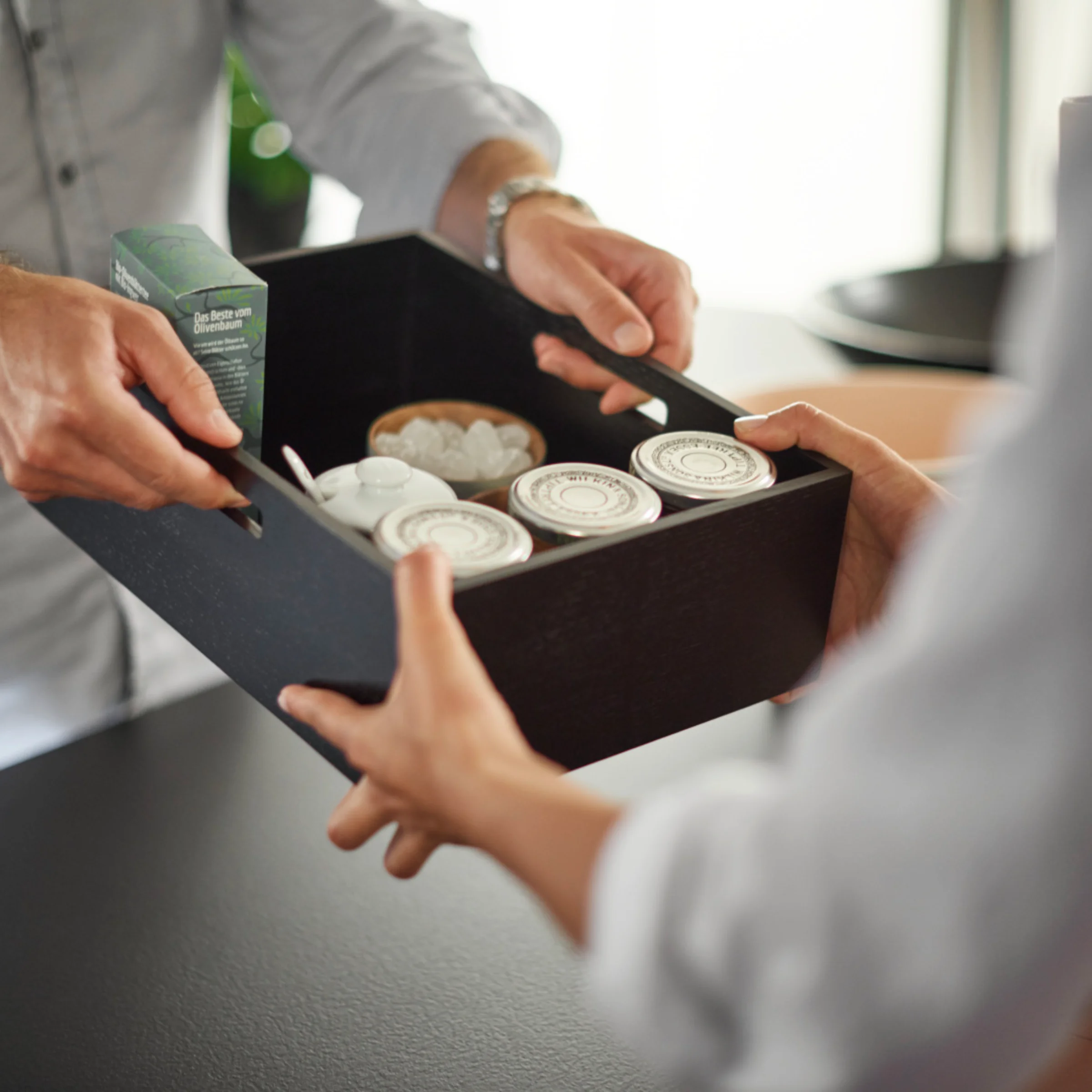 Zwei Personen übergeben sich eine schwarze Box mit Kosmetikartikeln in einem stilvollen Nolte SPA.