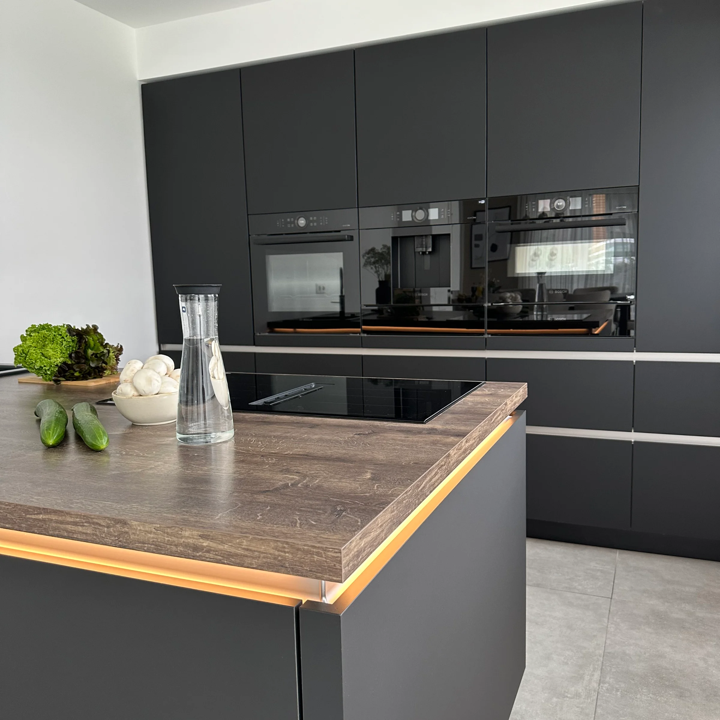 Eine moderne Küche mit dunklen Schränken und Kochinsel, stilvoll von Nolte Küchen gestaltet.
