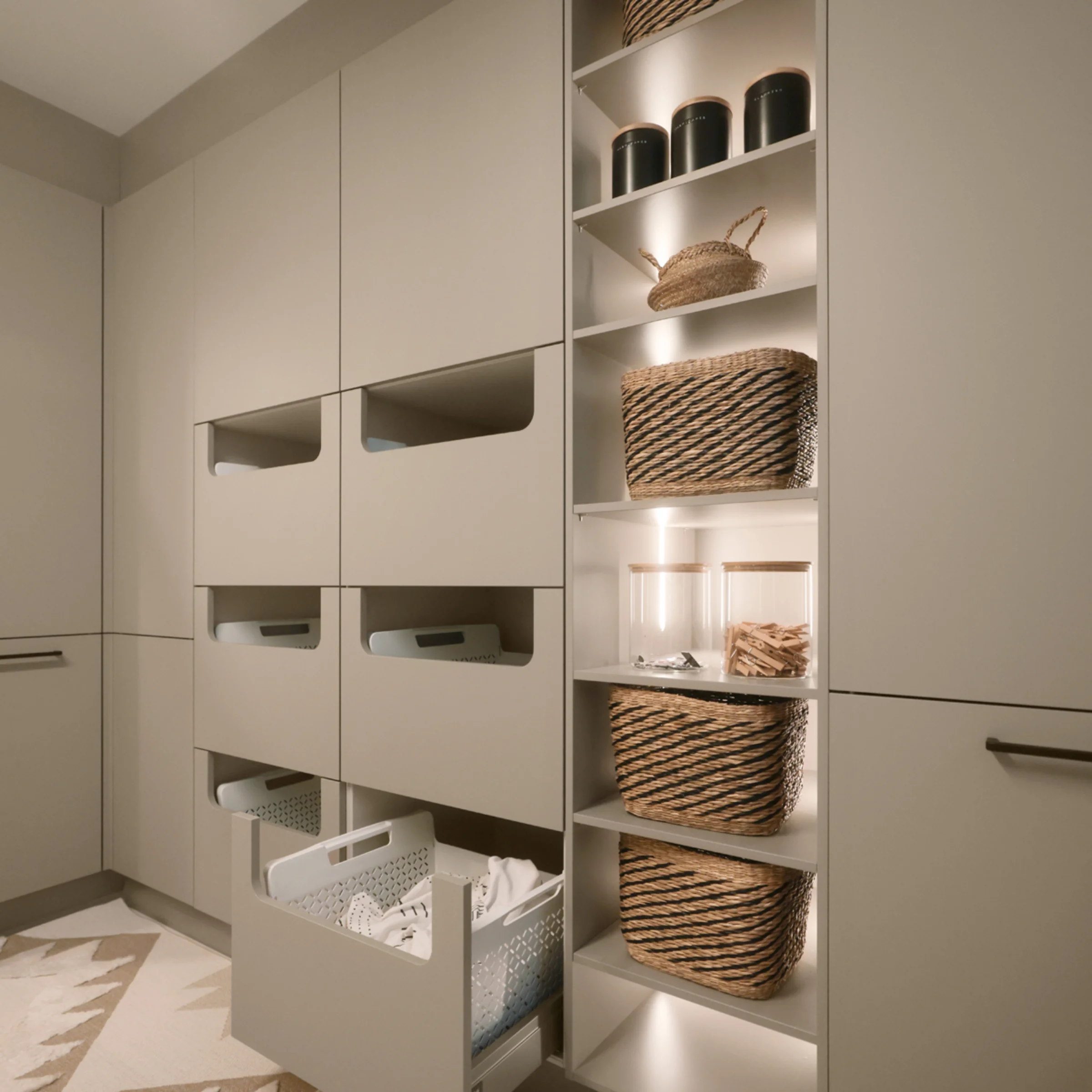 Ein Hauswirtschaftsraum mit offenen Regalen und Schubladen voller Körbe, präsentiert von Nolte Hauswirtschaftsräume.