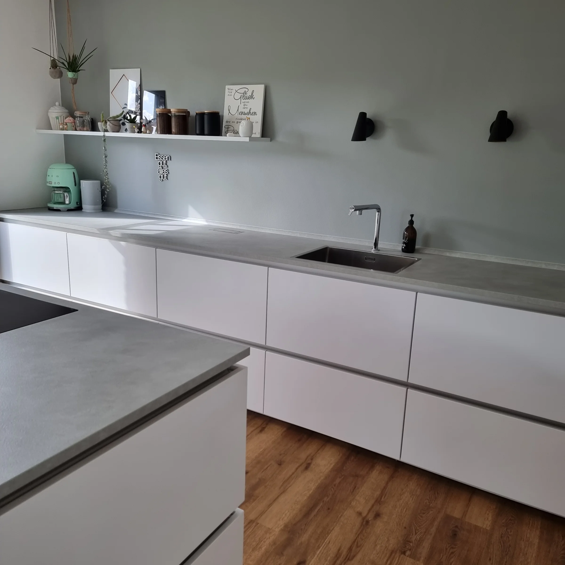 A modern kitchen with white cabinets and wood flooring, presented by Nolte Kitchen.